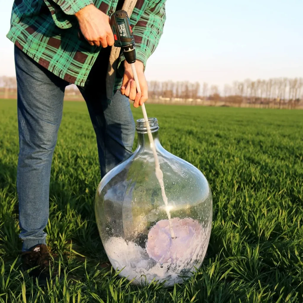 Weinballon reinigen: Mein Winzer-Geheimnis gegen hartnäckige Ablagerungen (absolut kratzfrei) 9 Cleaning a glass carboy bottle with a Pirouette rotary cleaner and a cordless drill.