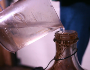 pouring water into demijohn